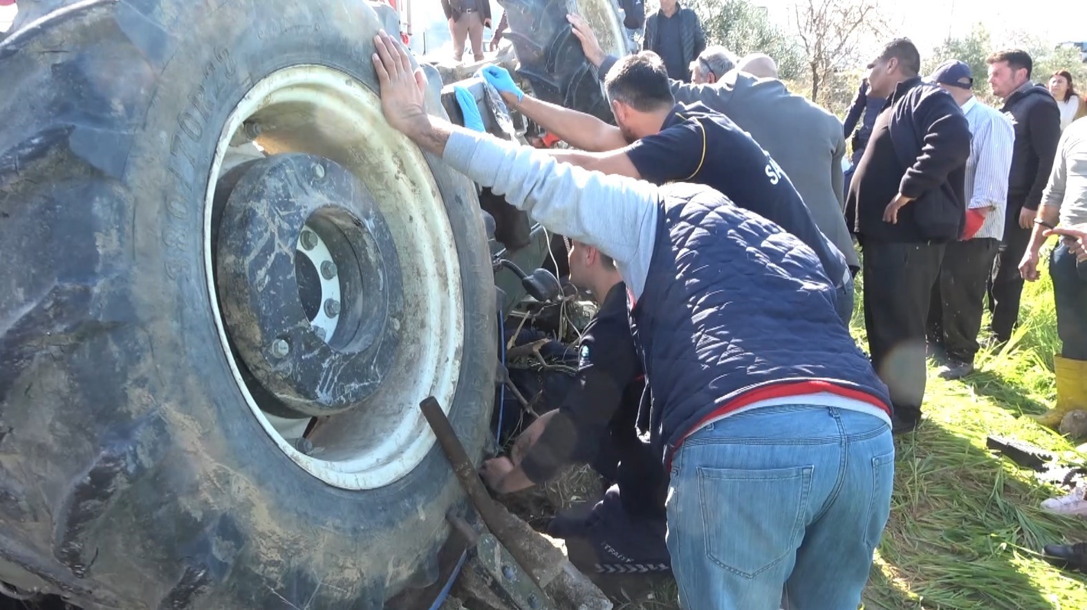 Devrilen traktörün altında kalan sürücüyü itfaiye ekipleri kurtardı
